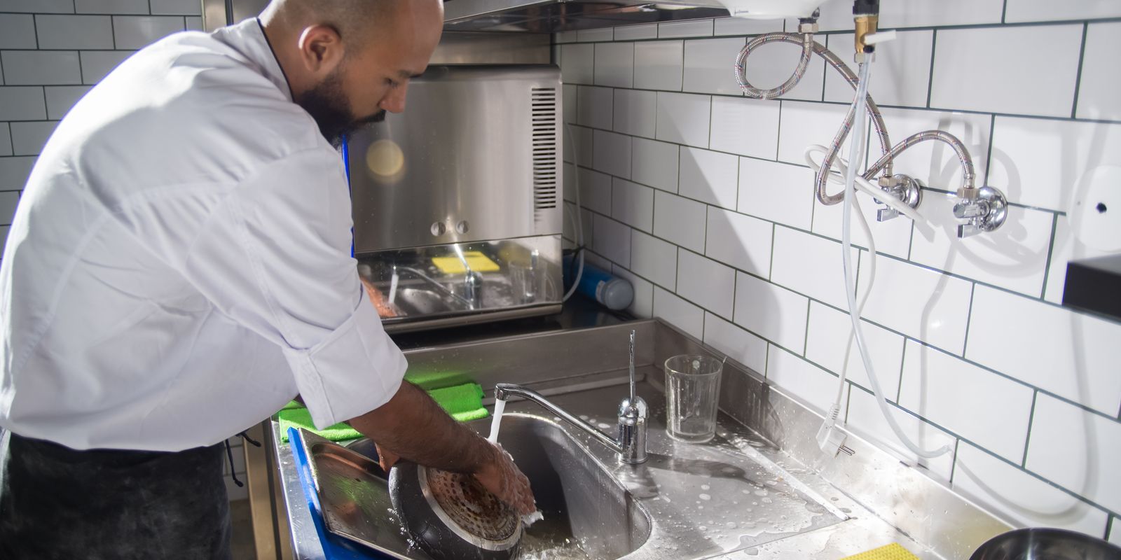 Kuvar pere pribor u inox sudoperi profesionalne kuhinje — HACCP higijena